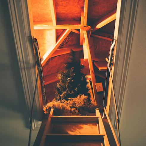 7. Air-Quality Controller View up a ladder to an attic with an artificial Christmas tree as part of Home Network The Secret to Storing Holiday Decorations in Small Spaces
