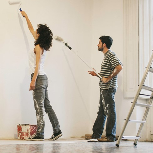 Choose Lighter Paint Colours A couple painting a wall white