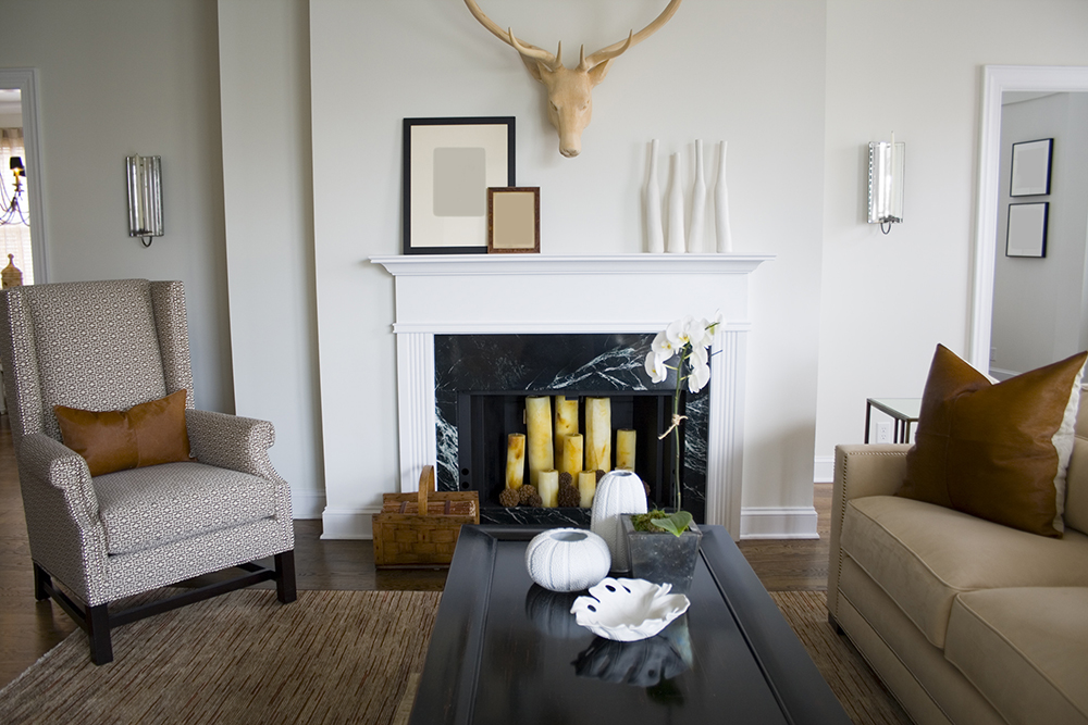 Chic neutral living room with white walls and beige furniture. The white fireplace is filled with 8 beige pillar candles.