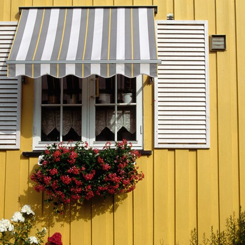 Install Awnings An awning over the window of a yellow house