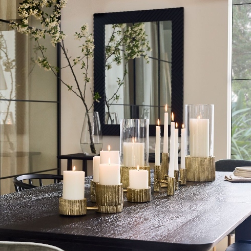 Ambient Lighting Metal candle holders with various sized candles on a tabletop