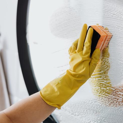 11. Say Goodbye to Pet Hair With Rubber Gloves a person with yellow rubber gloves cleaning a mirror