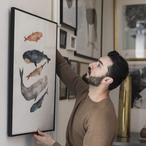 What Kind of Hanging Hardware Do I Need? man hanging painting on wall at home