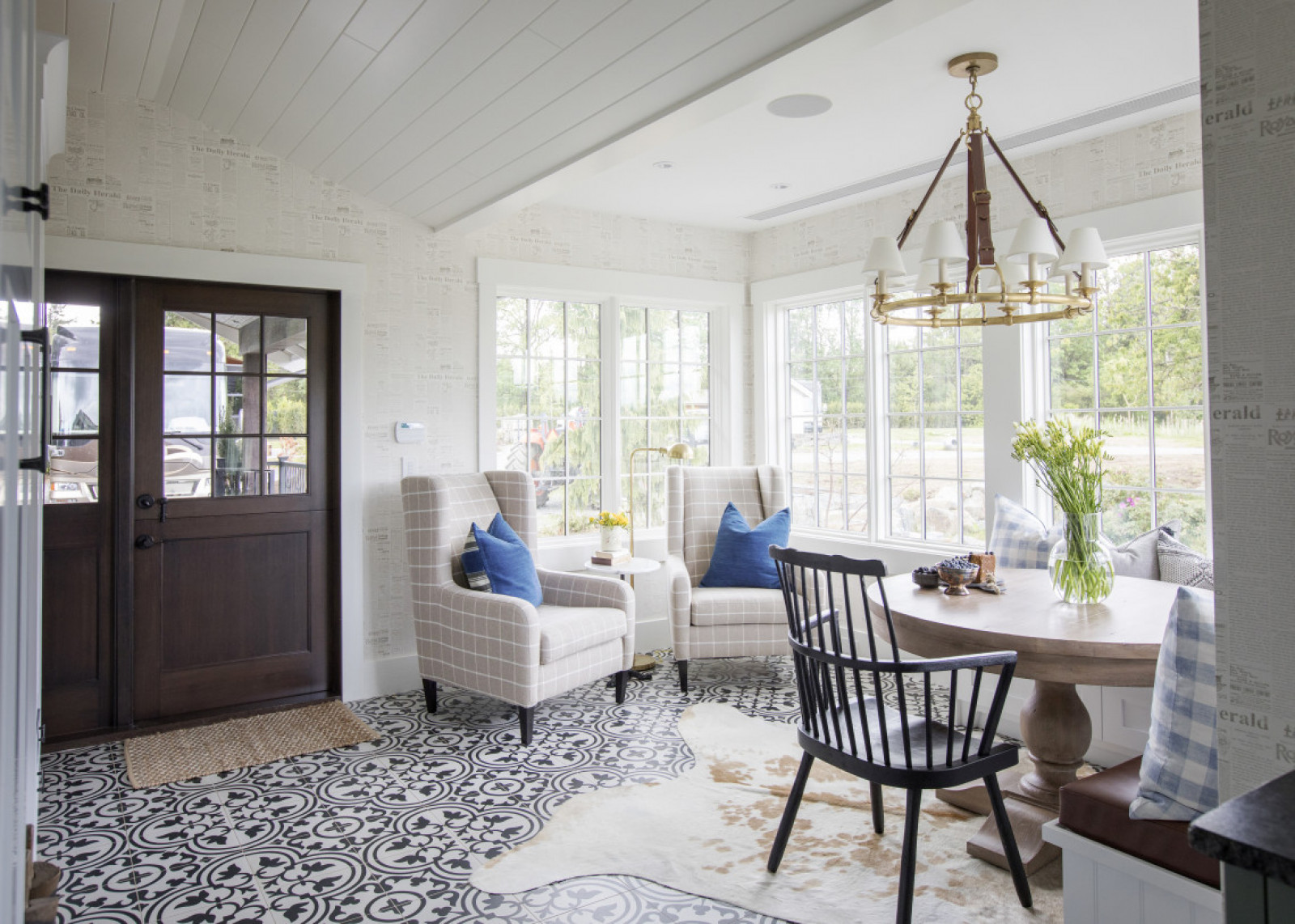 Best Seats in the House windowed eating nook beside dark brown door, two wing back chairs, round table, chair and black and white patterned floor