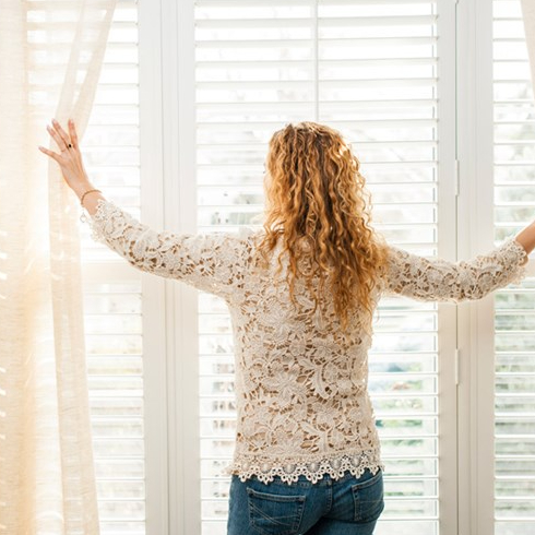 Use Window Treatments Woman opening curtains