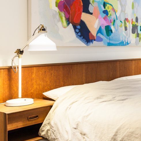 Use Different Light Sources A white basement bedroom with pops of colour with the artwork and lamps