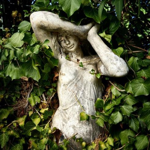 Frozen in Time White statue of a Grecian woman covered in ivy as part of memorial garden ideas
