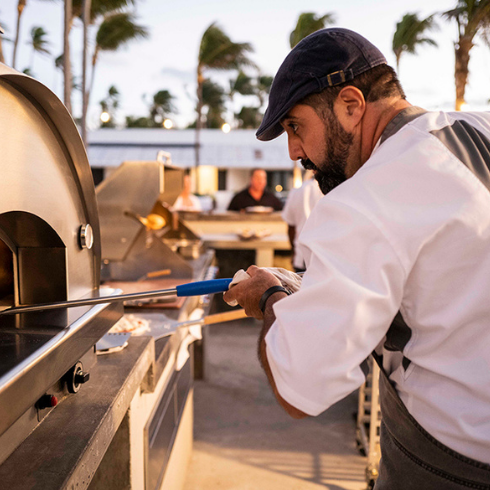 What Kind of Food is There? Man preparing pizza outside of Caerula Mar Club